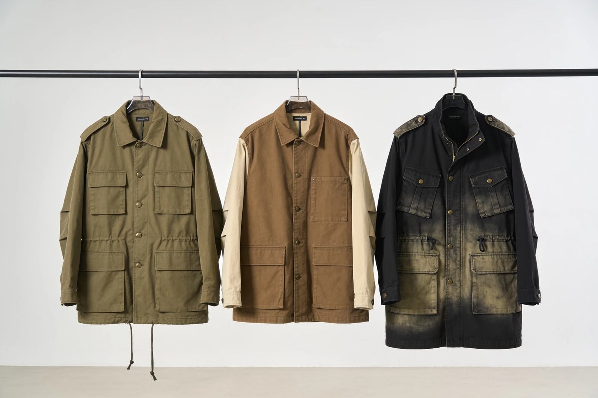 Representative lot of field and utility jackets - olive M-65 field jacket, brown work jacket with contrast sleeves and a washed black field jacket on a rail