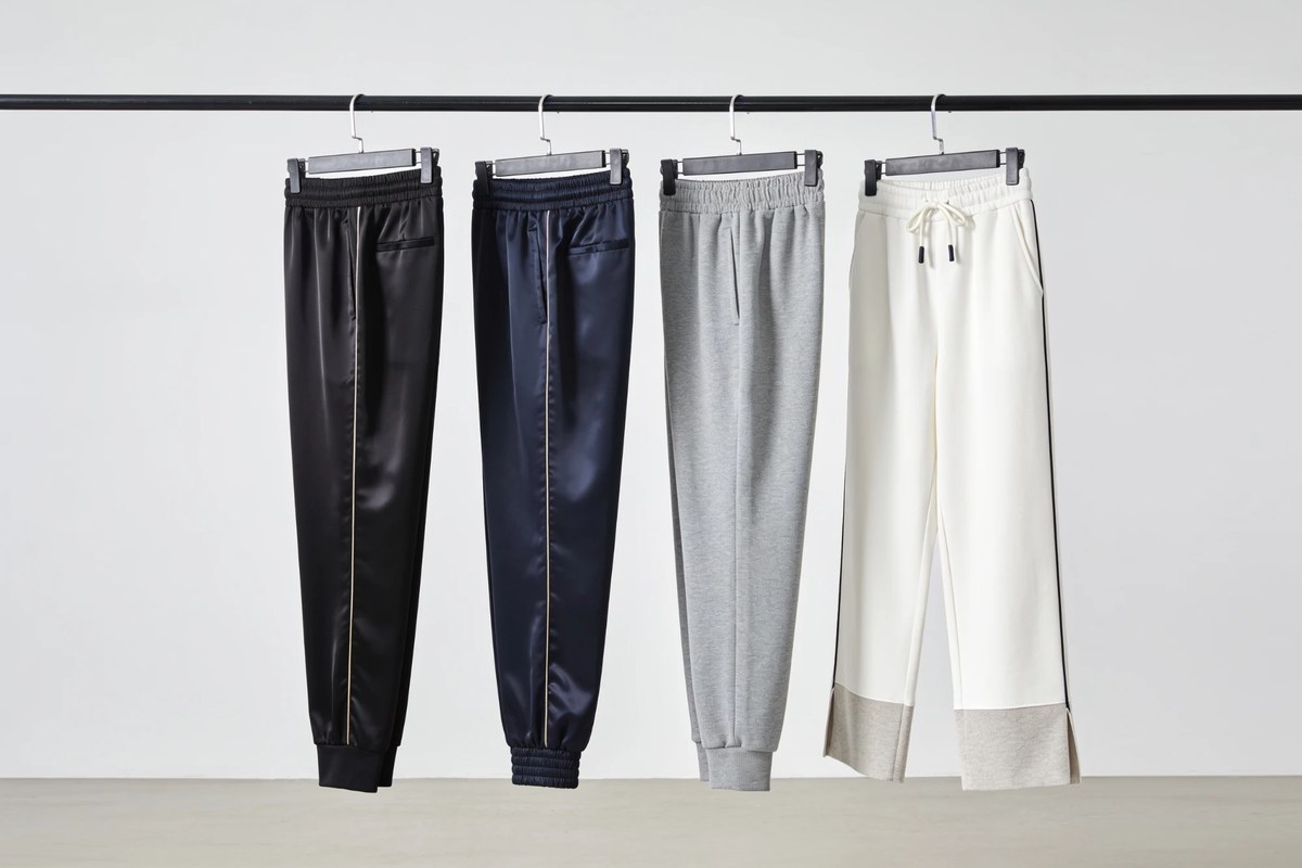 Representative lot of track and jersey bottoms - black and navy satin track pants with grey and cream jersey joggers on a rail
